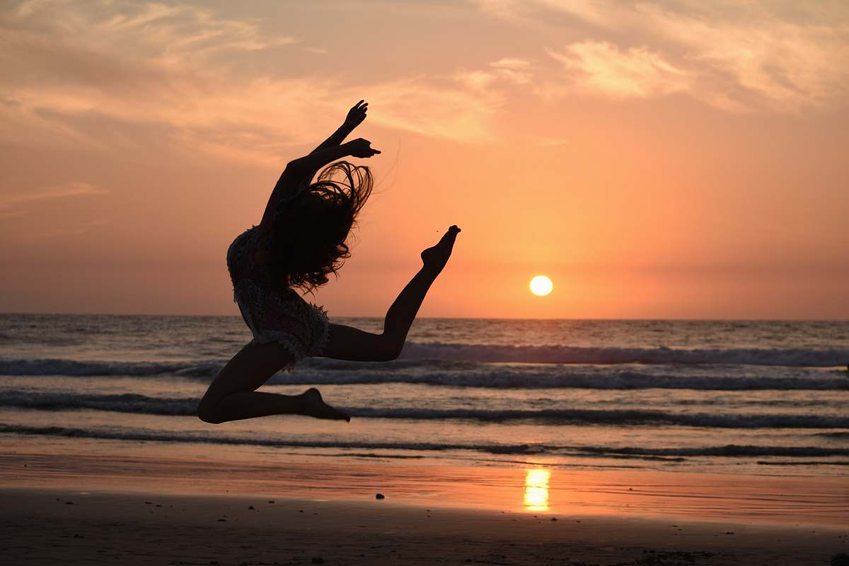 silhouette silhouette of woman jumping during golden hour sea
