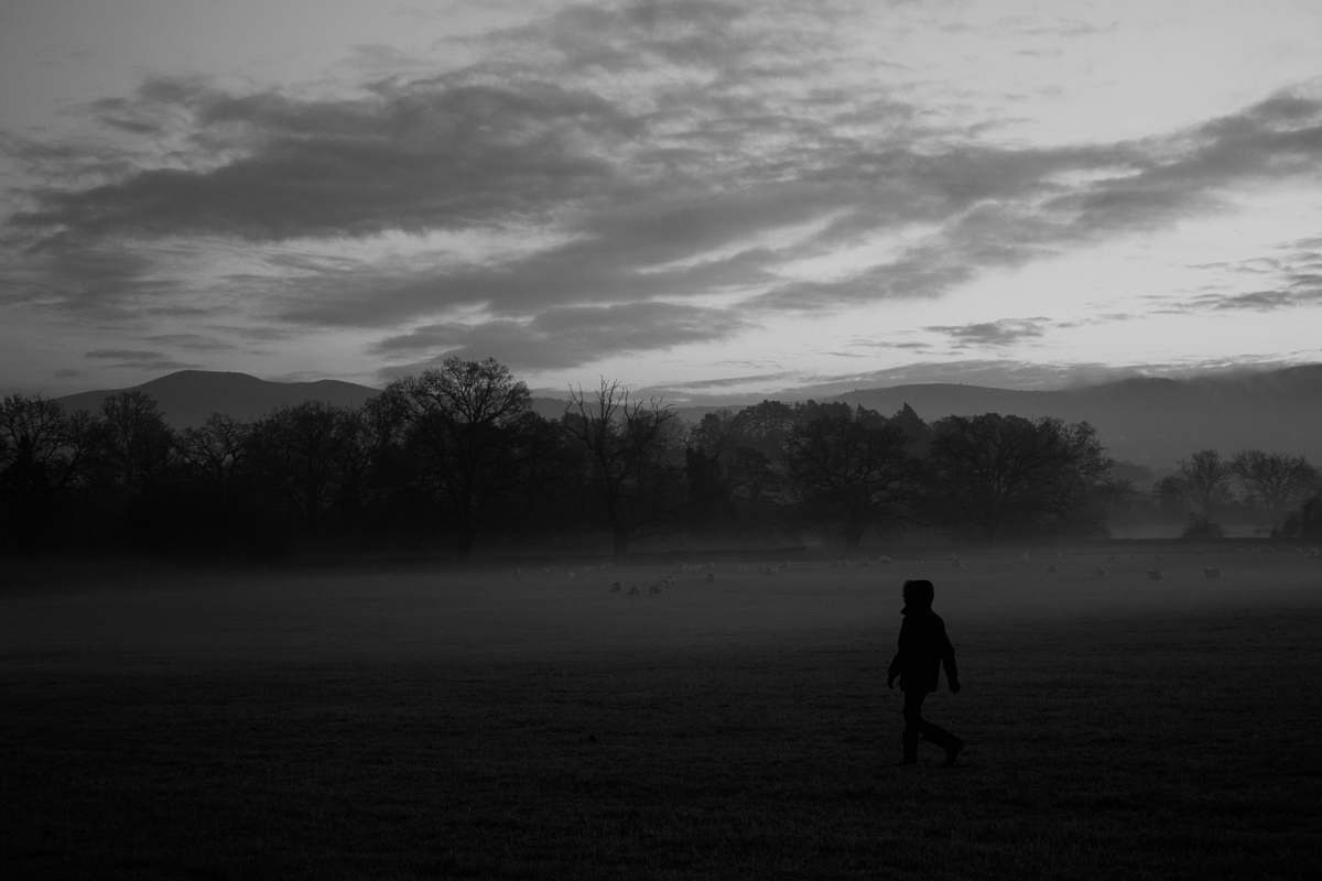 person grayscale photo of person walking in the middle of forest human