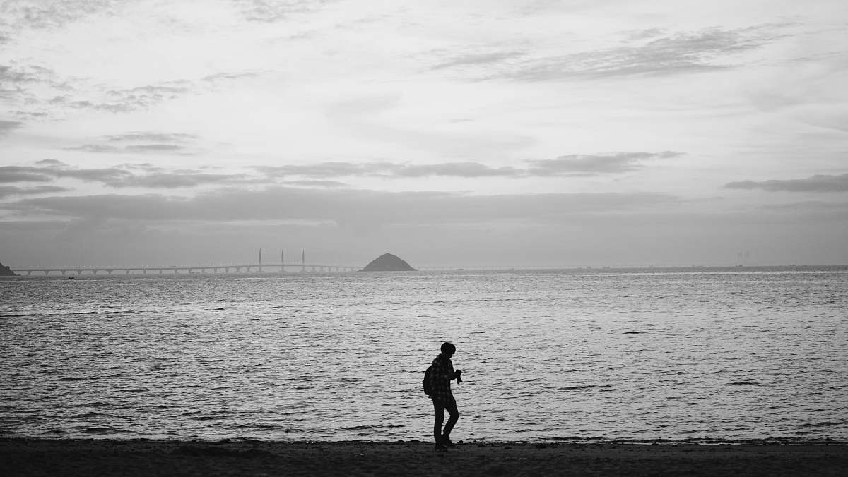 grey grayscale photography of person on seashore human