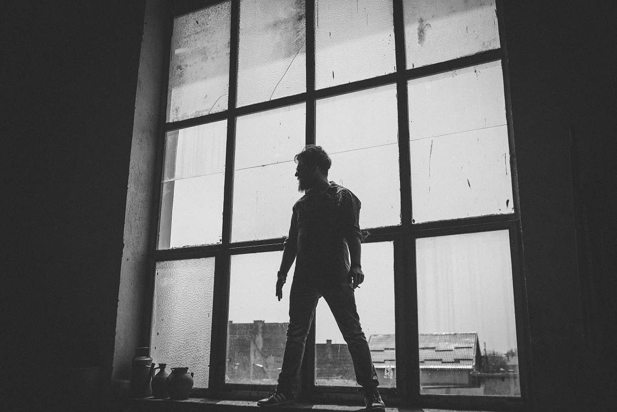 people man standing against the glass window grayscale photography grey