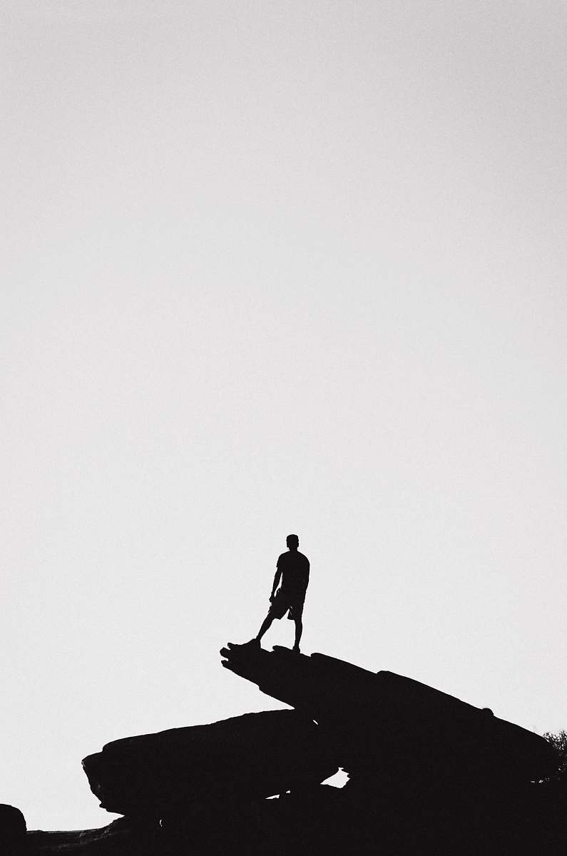 silhouette person standing in a rock formation grey-scale photography person