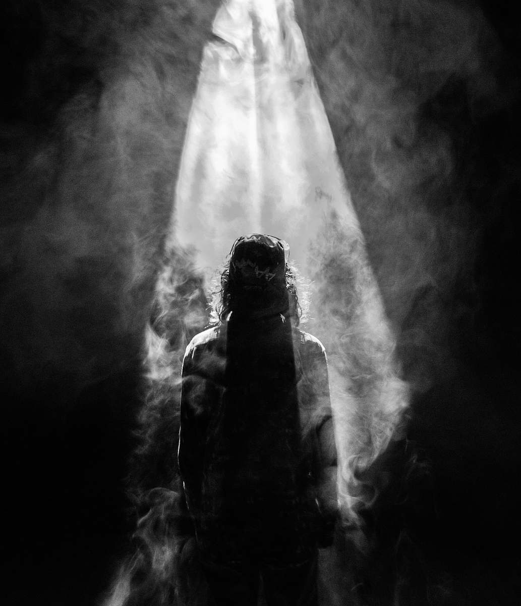 smoke photograph of person facing opposite in smoky spotlight grey