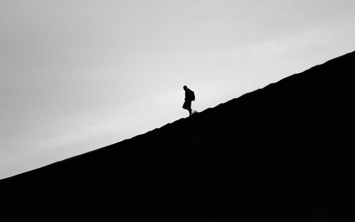 silhouette silhouette photo of person walking on mountain grey