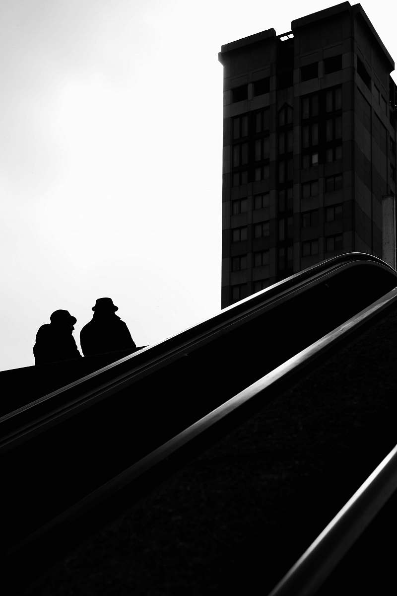 handrail two people riding escalator banister