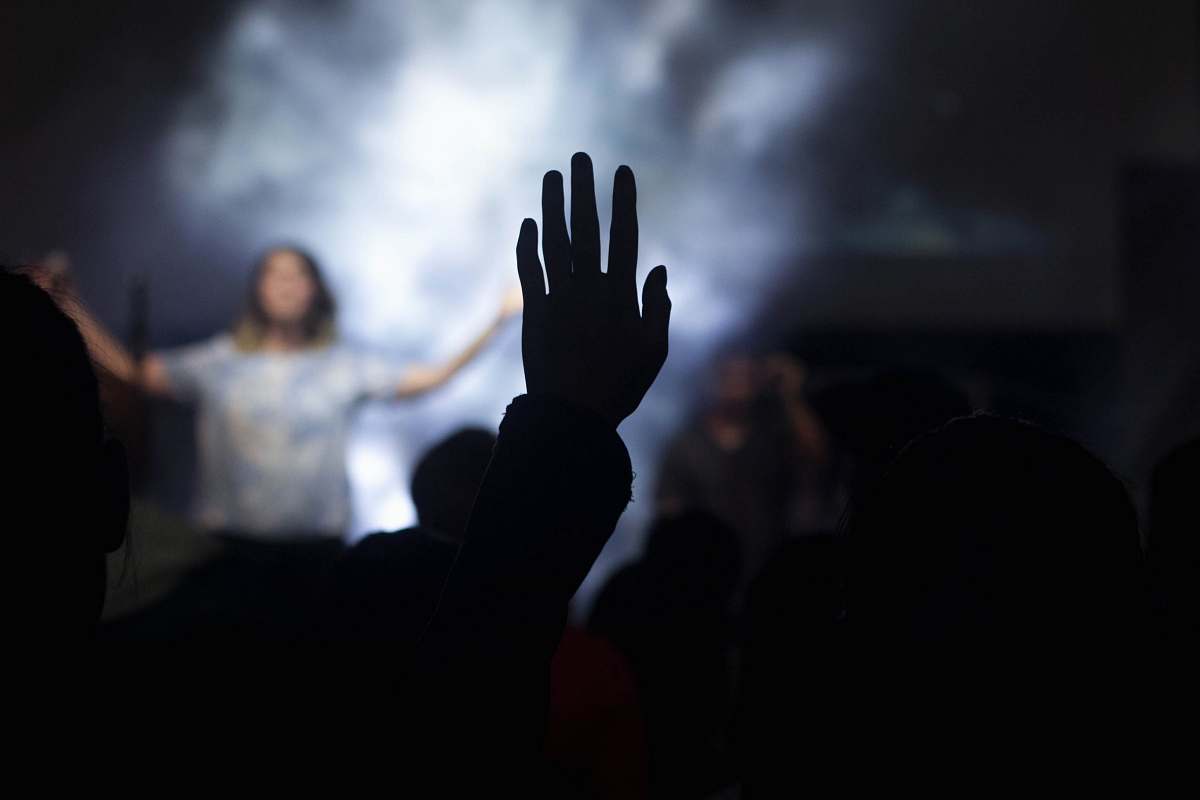 music silhouette of person with right hand on air in front of woman on stage worship