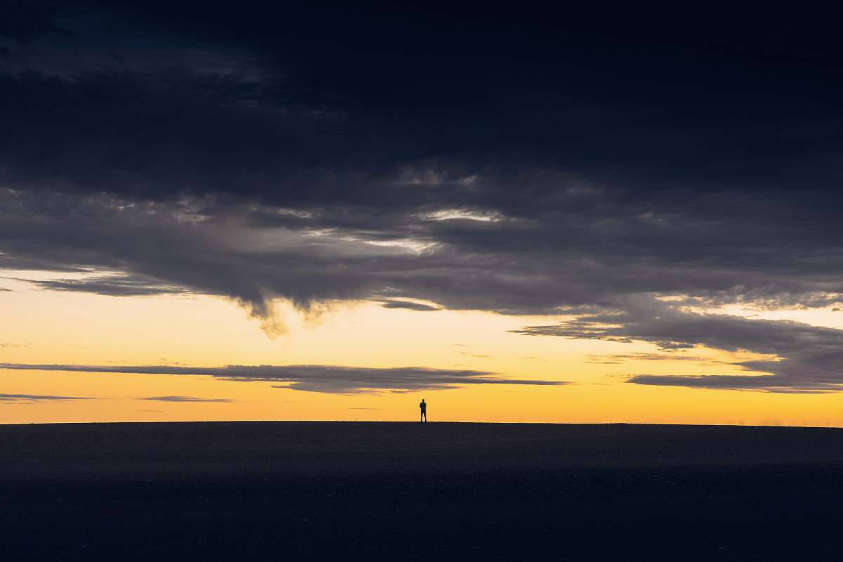sunset silhouette of person standing on hill during sunset cloud