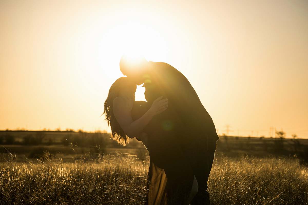 light man and woman kissing on grass field during day time godley