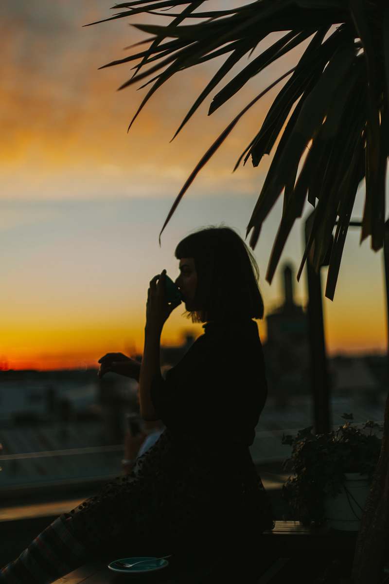 vase silhouette woman drinking from teacup during golden hour pottery