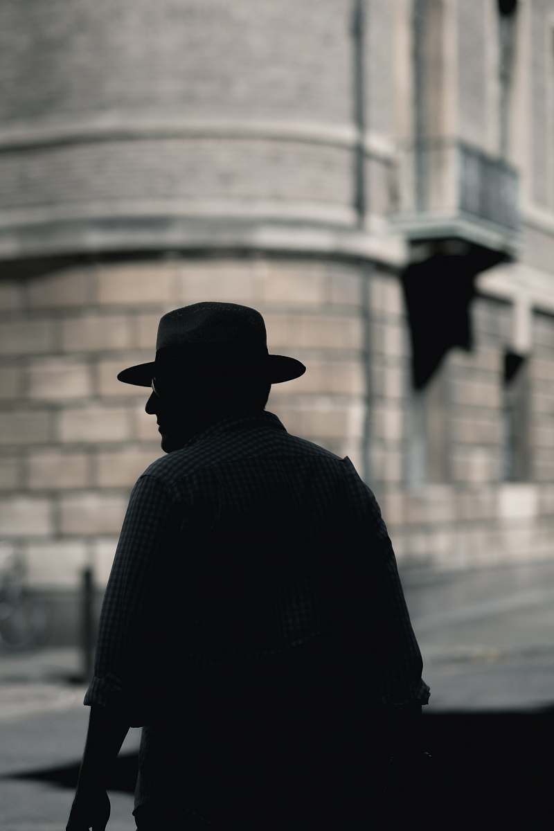 cambridge silhouette photo of a man with hat standing near concrete building at daytime man