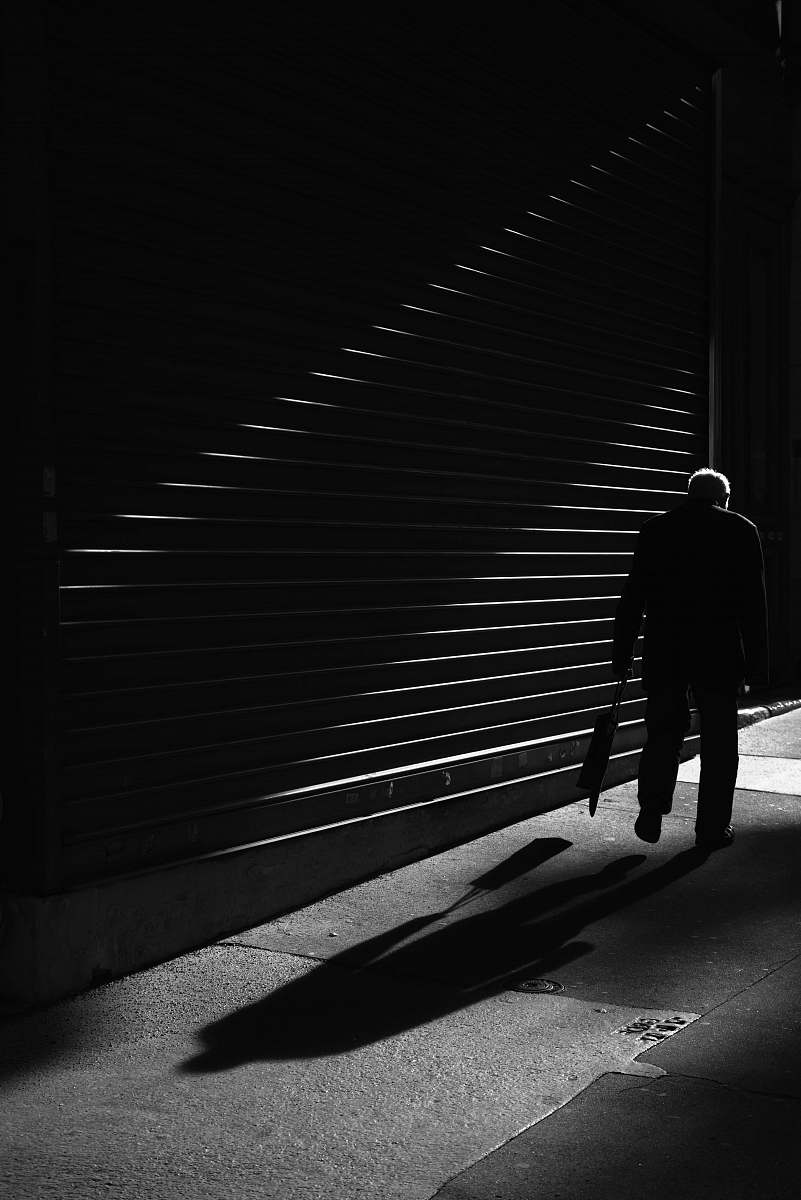 black-and-white grayscale photo of man standing on front of roller shutter pedestrian