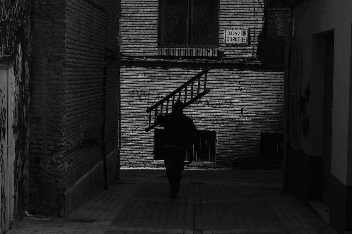 people grayscale photography of man carrying ladder black-and-white