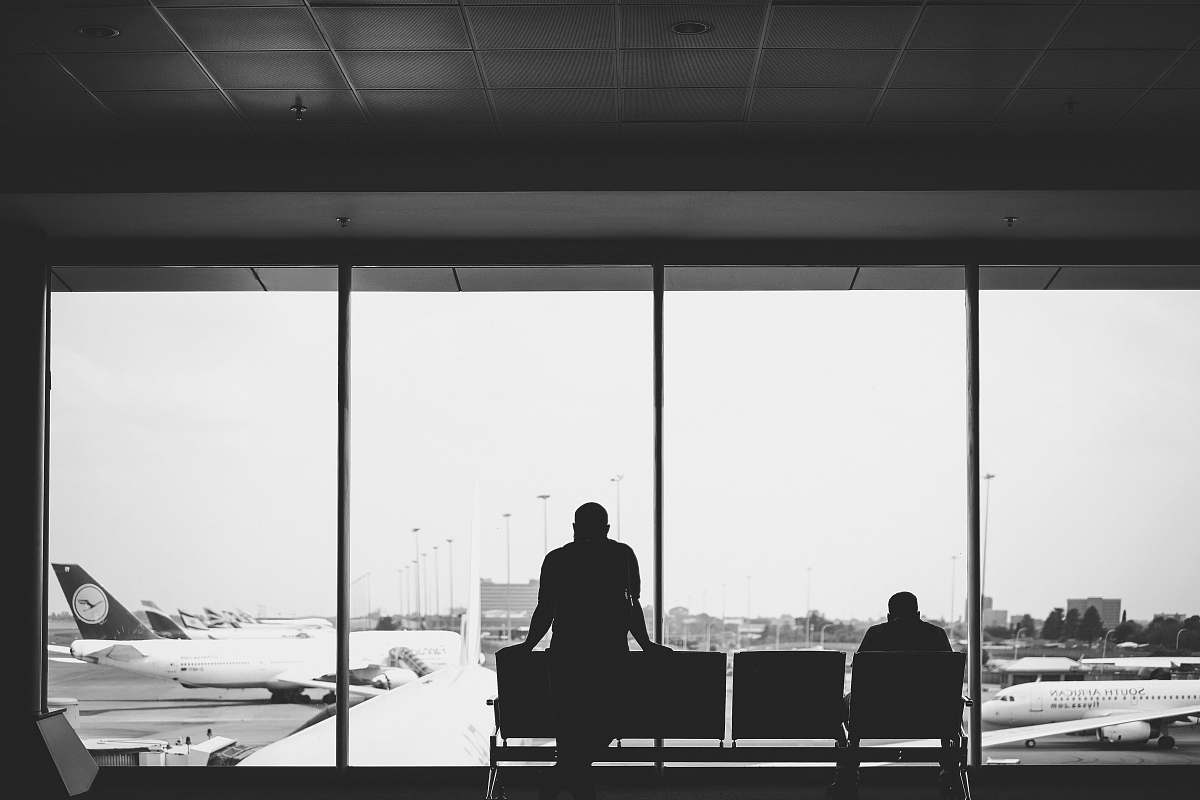 person grayscale photography of standing person near sitting person black-and-white