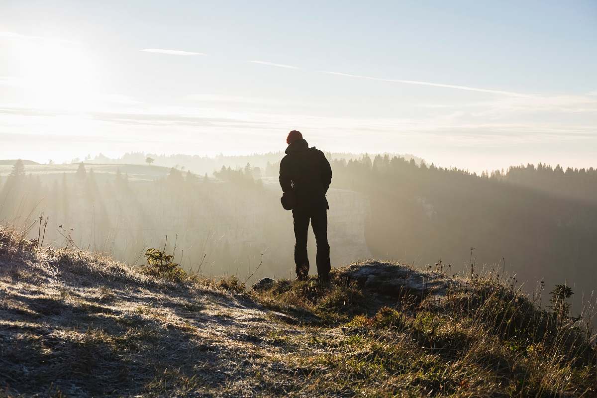 person man standing on cliff near trees during daytime people