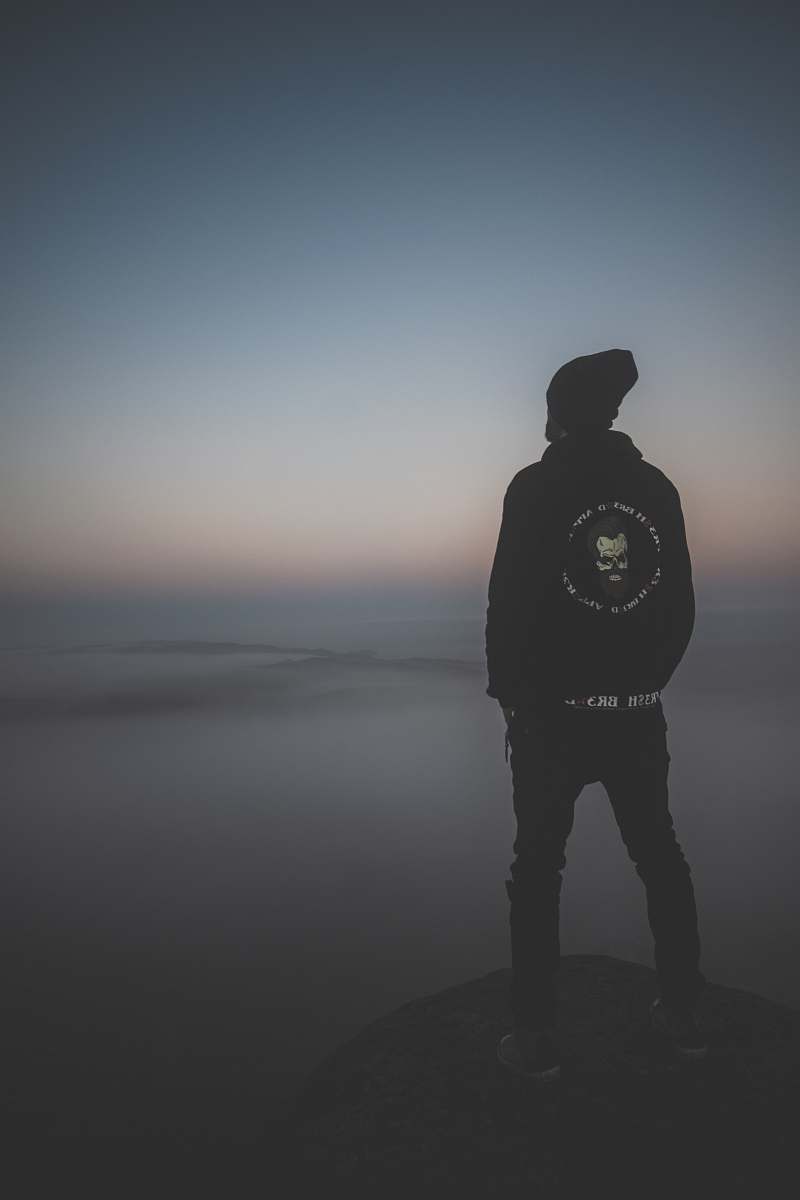 grey man standing on peak at daytime standing