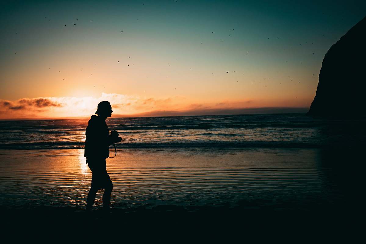 person man walking on seashore at golden hour people
