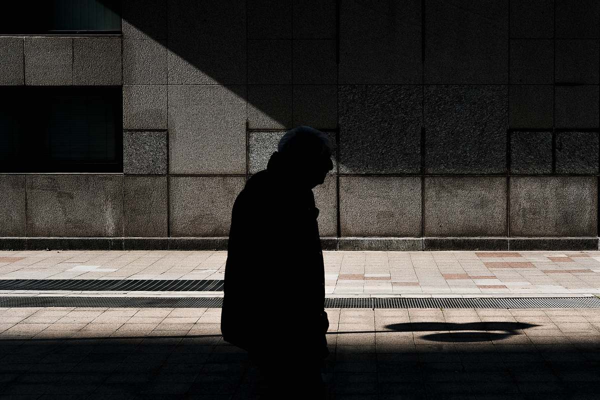 person man walking on street under shade of sun during daytime pedestrian