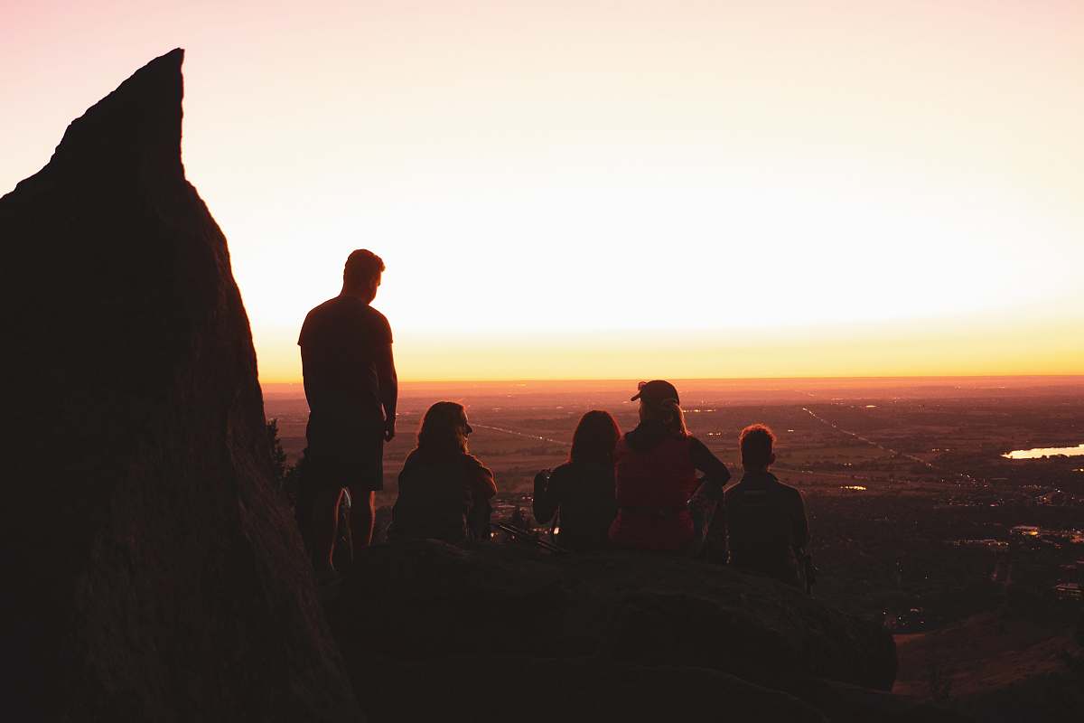 person people sitting and standing on rocky cliff during day outdoors