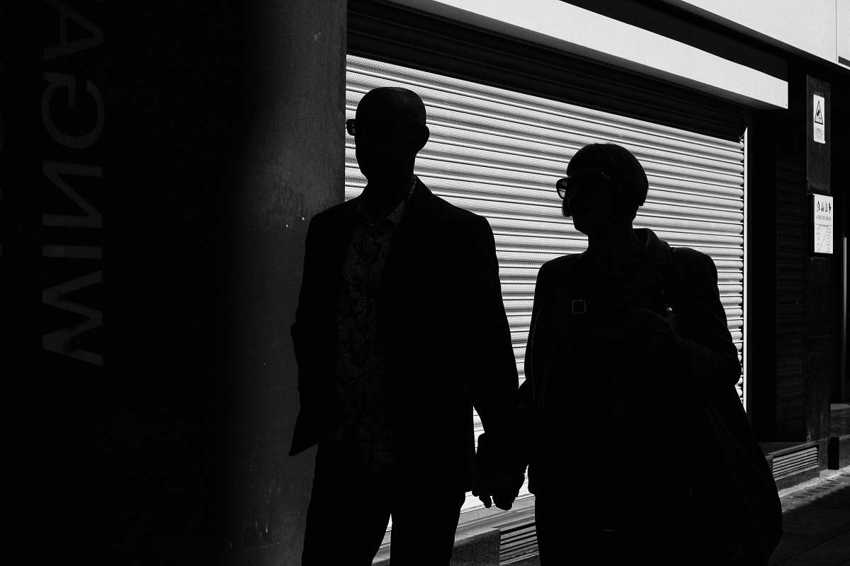 people silhouette of man and woman walking inside building black-and-white