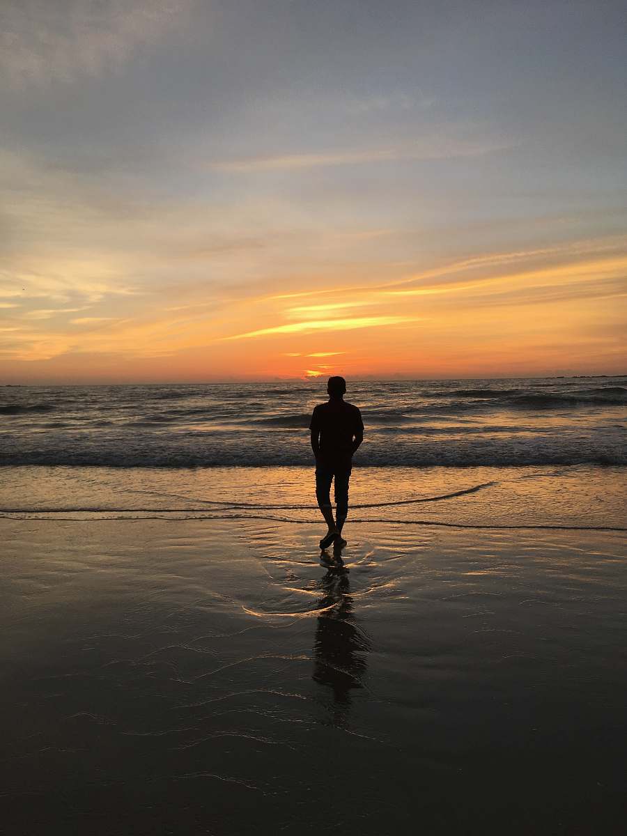 person silhouette of man standing on seashore standing