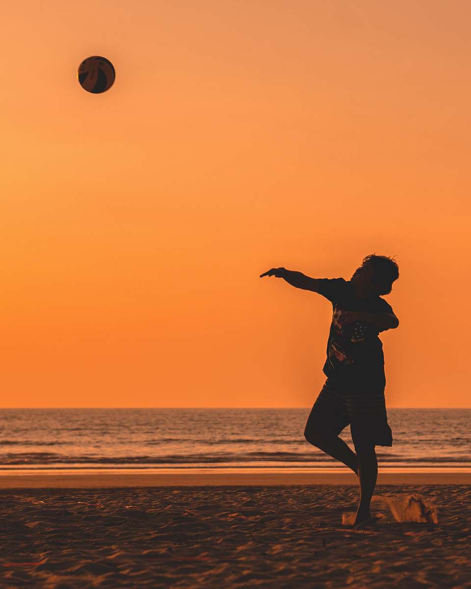 people silhouette of man throwing ball near ocean at golden hour person