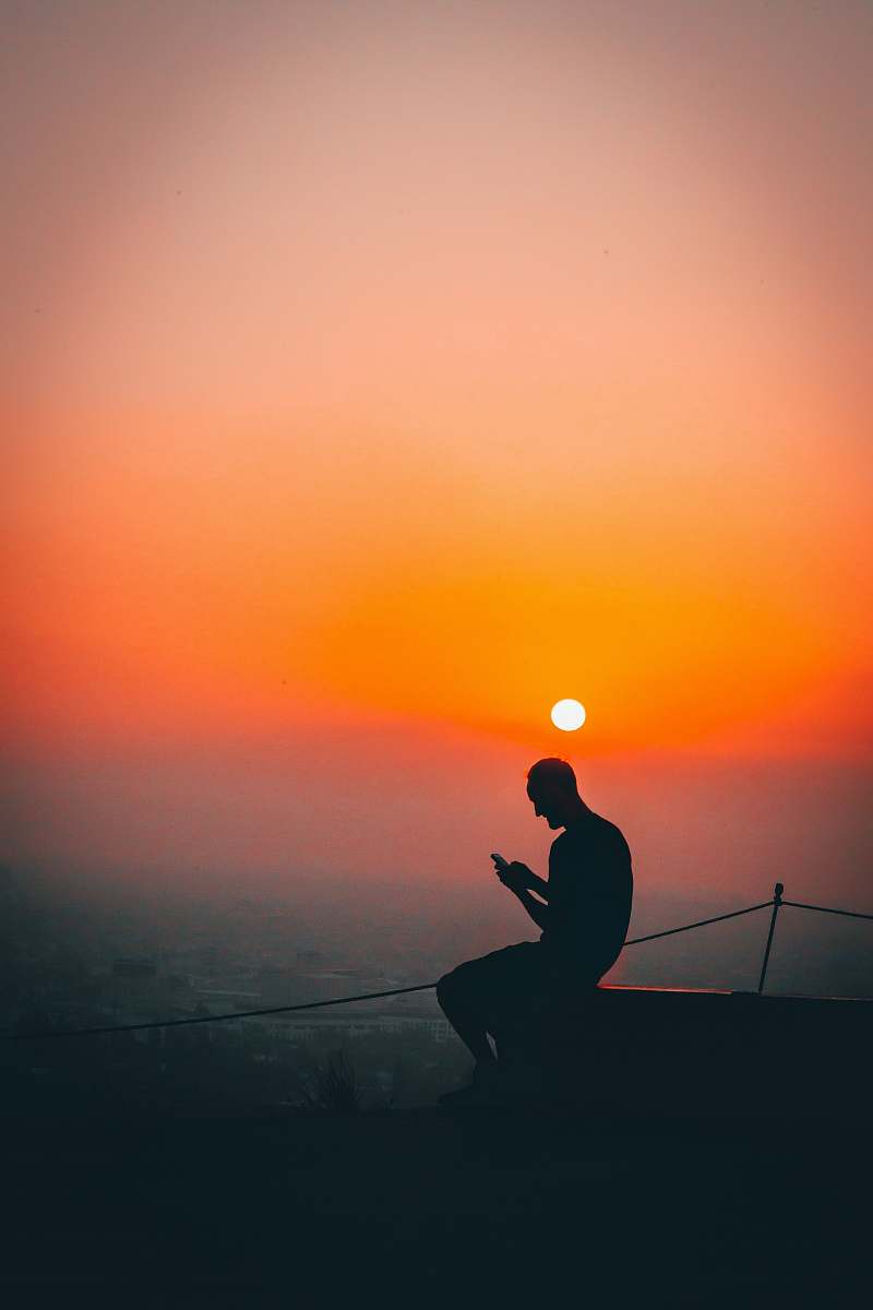 person silhouette of man using smartphone outdoors