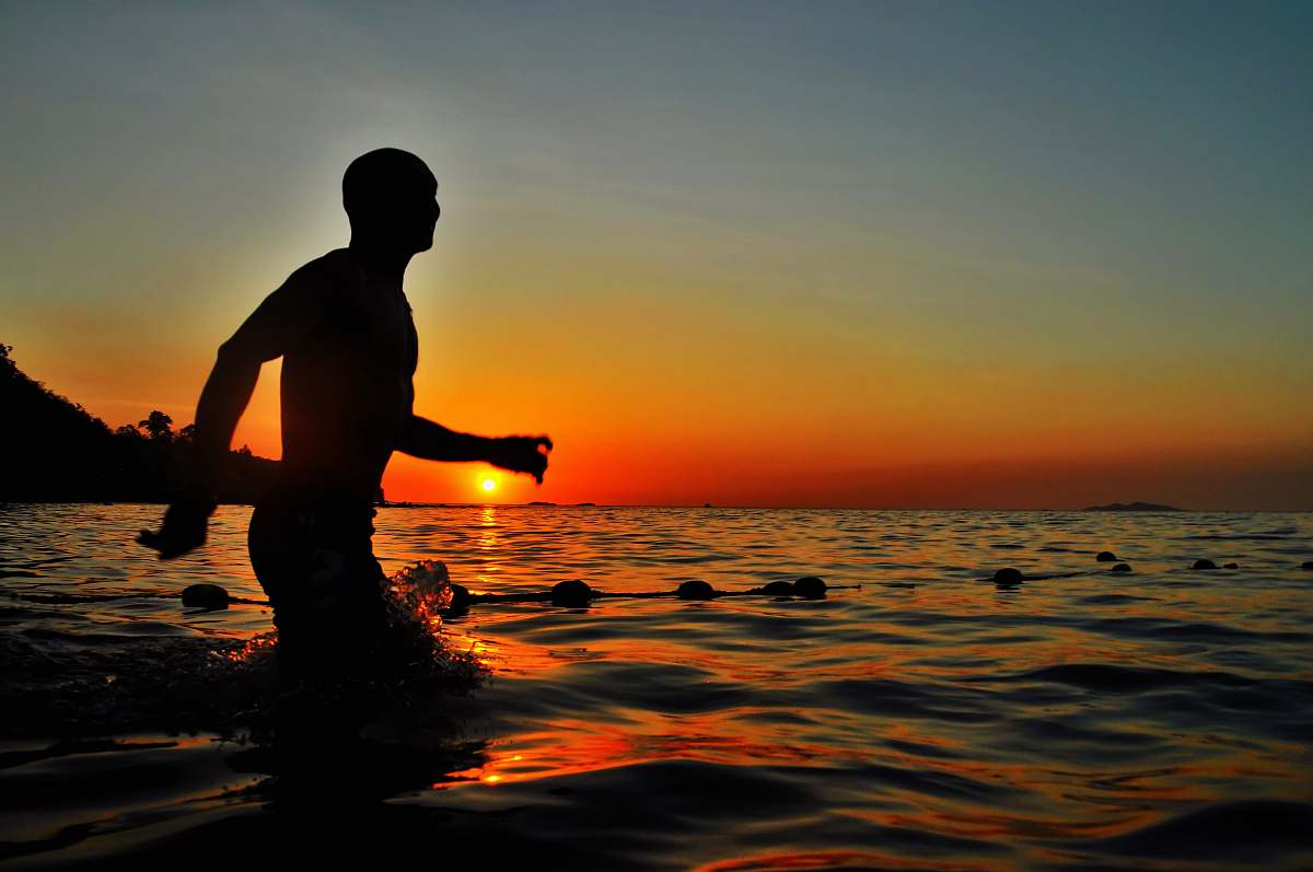 person silhouette of man walking in body of water people