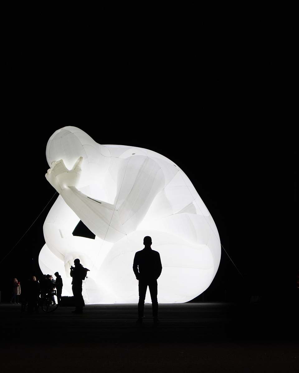 person silhouette of people standing beside lighted statue silhouette