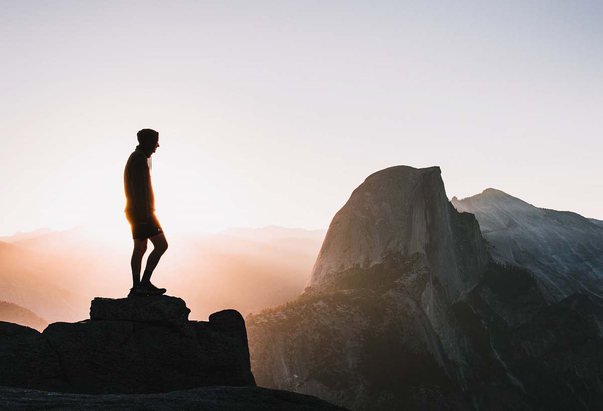 person silhouette photo of man standing on hill standing