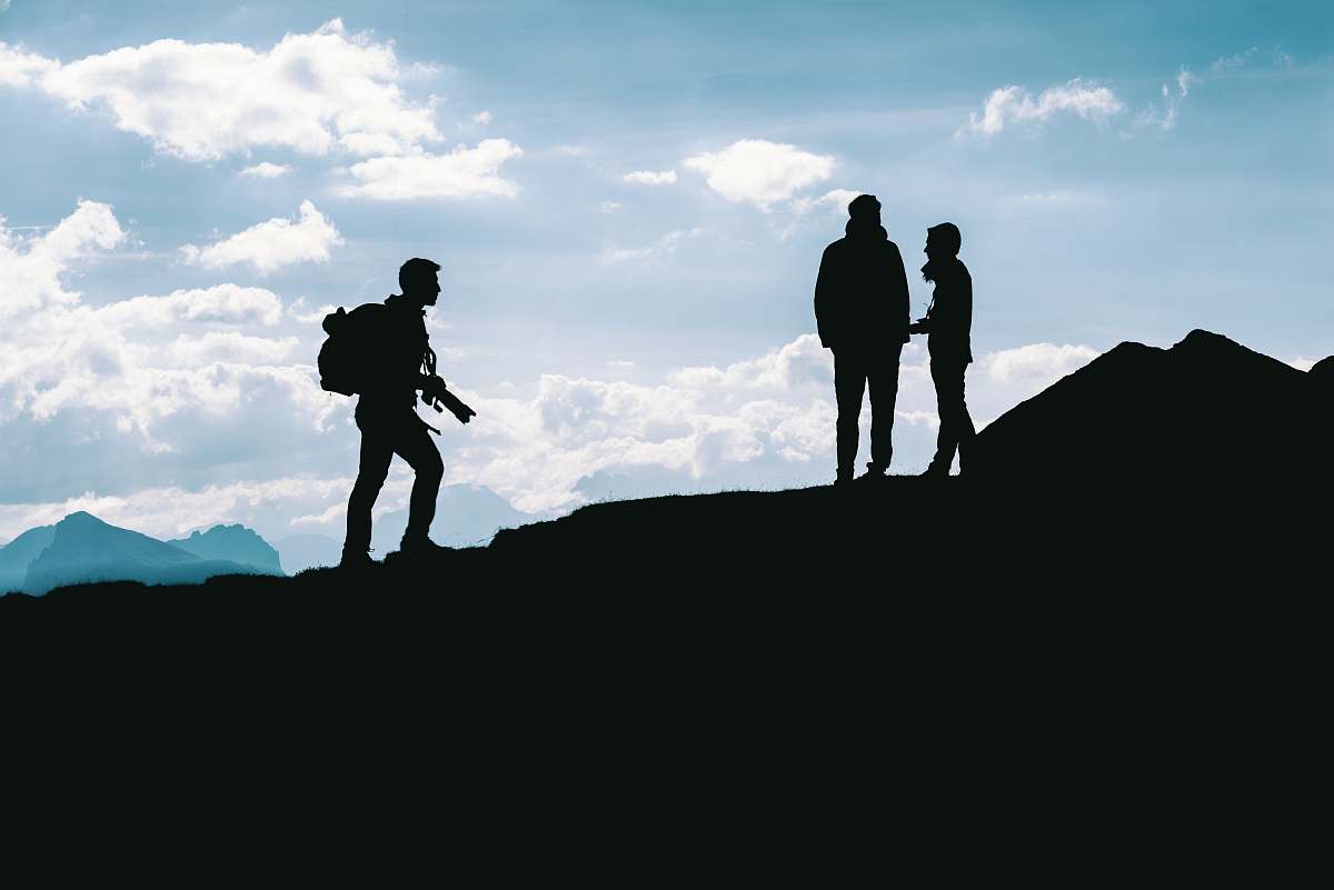 person silhouette photo of three person standing on top of cliff people