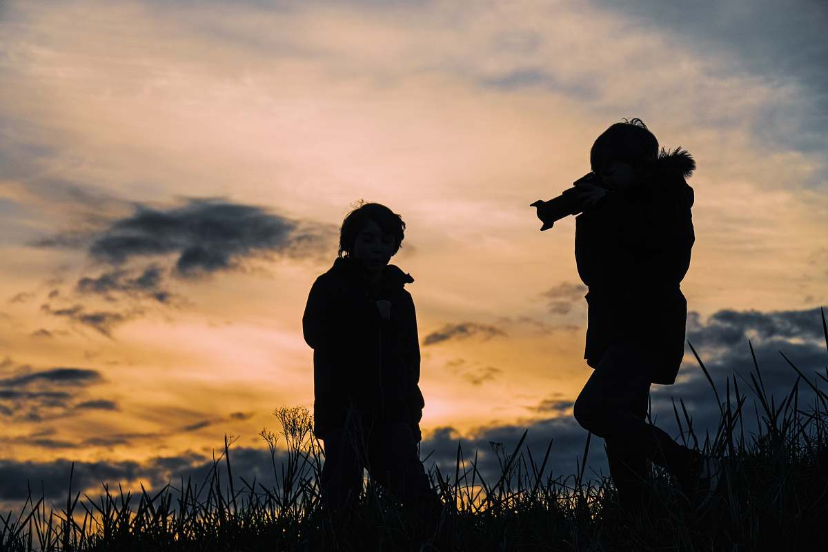 person silhouette photo of two person taking a photo at grass fields people