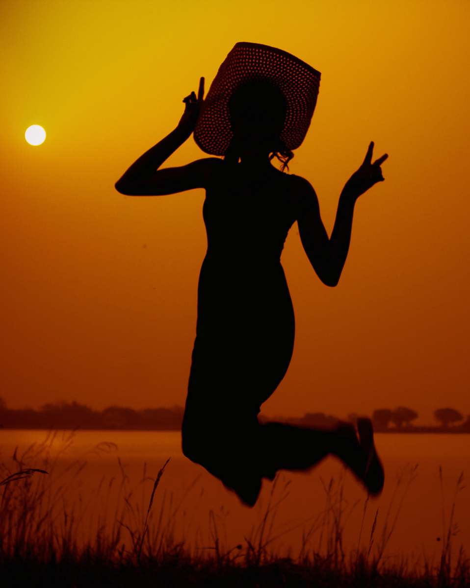 person woman in hat jumping during golden hour apparel