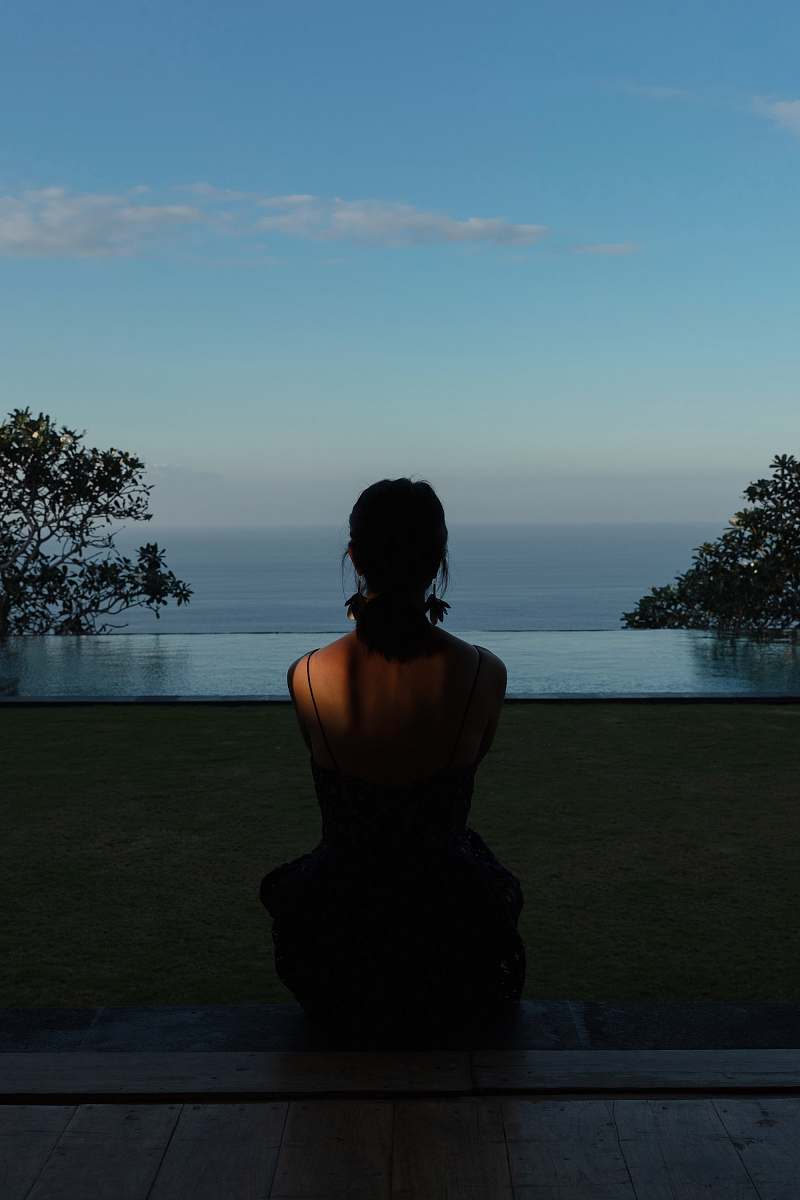 silhouette woman sitting on field during daytime back
