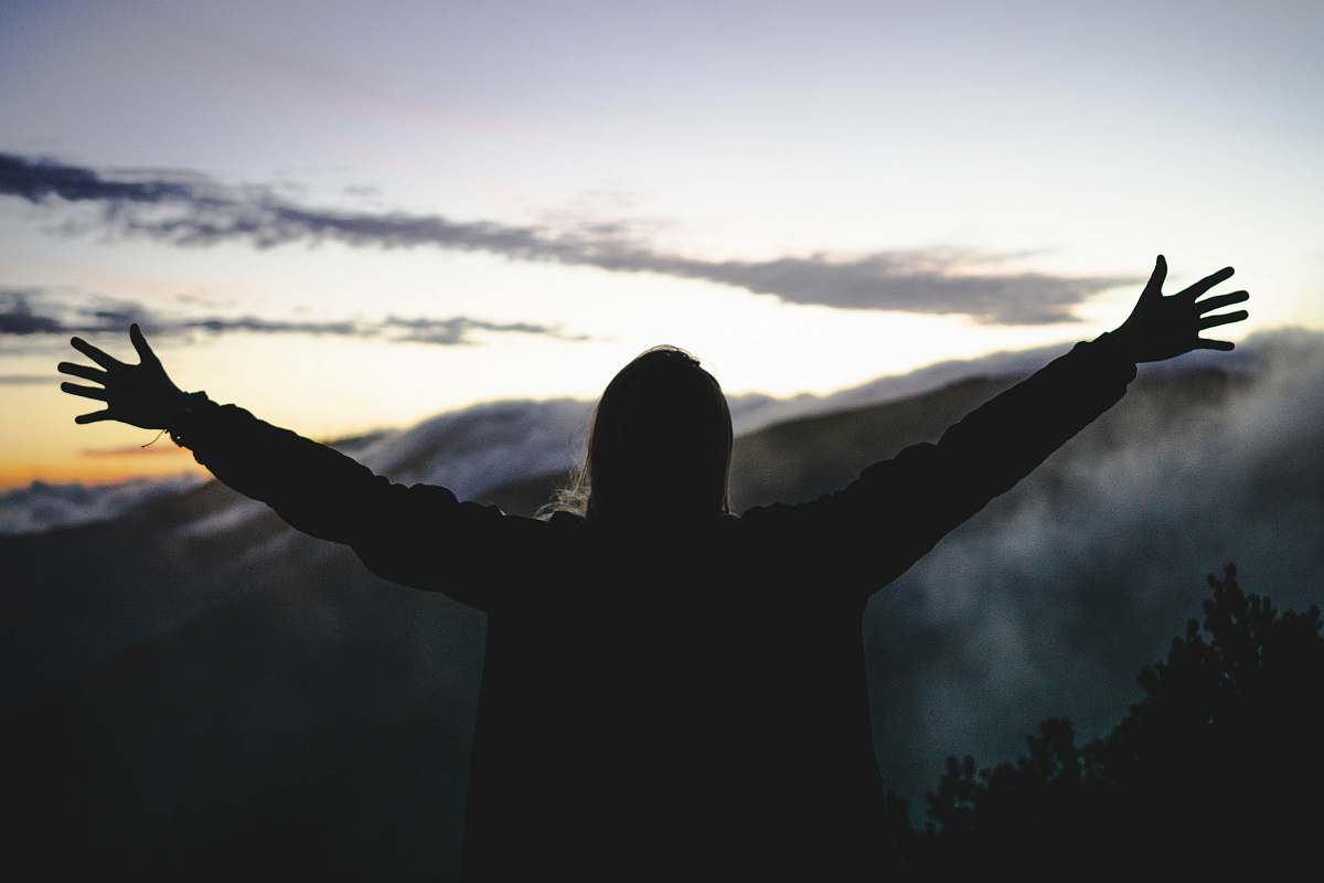 flare silhouette of man standing front of mountain silhouette