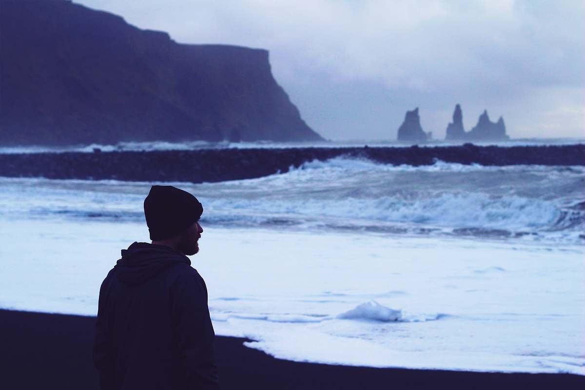 beach man standing on seashore looking at water waves ocean