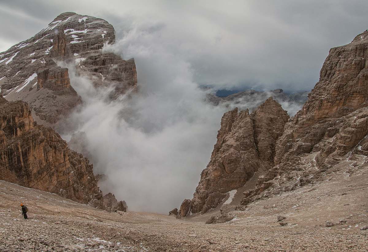 slope landscape photography of foggy mountain rocks descent