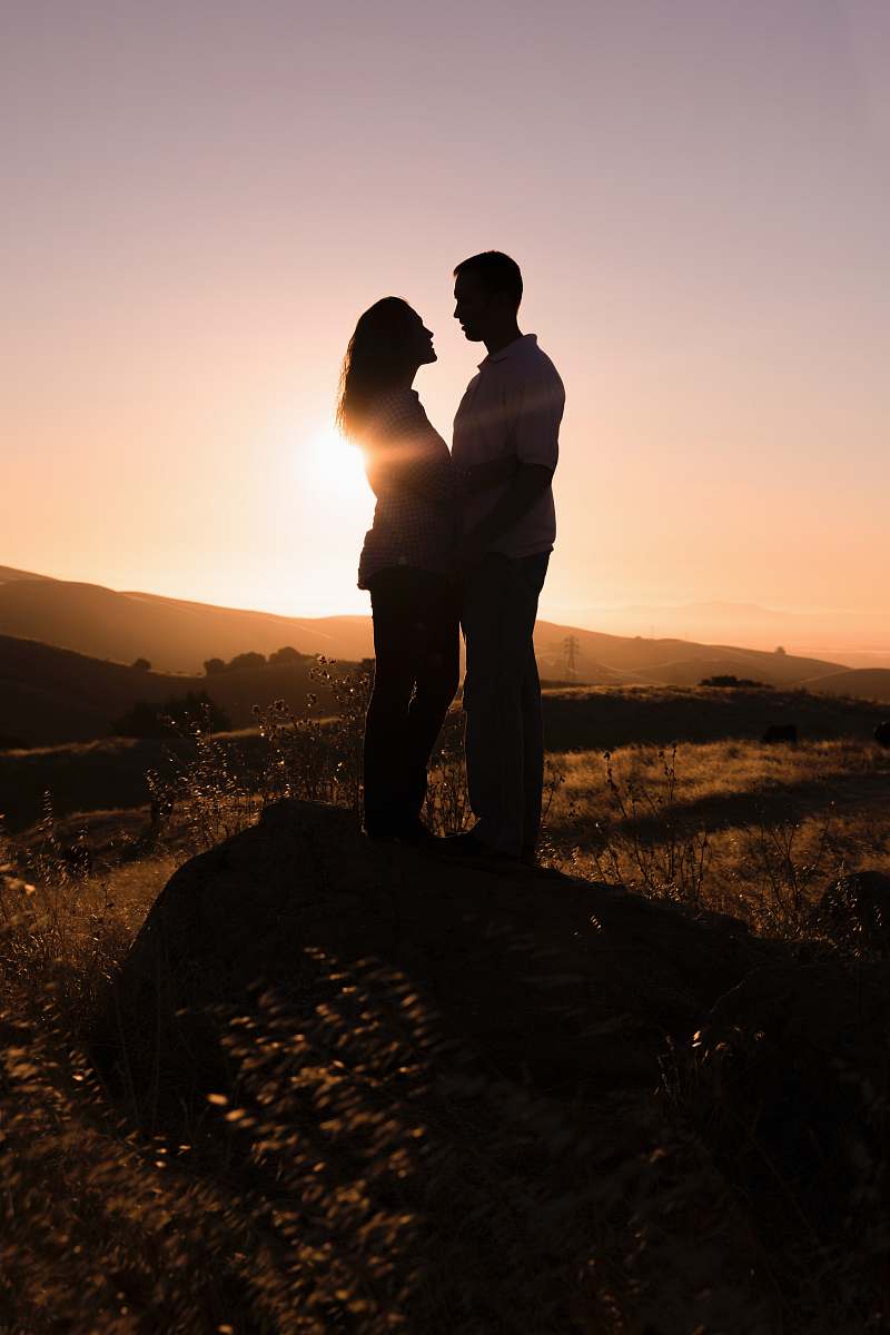 human man and woman standing on rock facing each other during day person