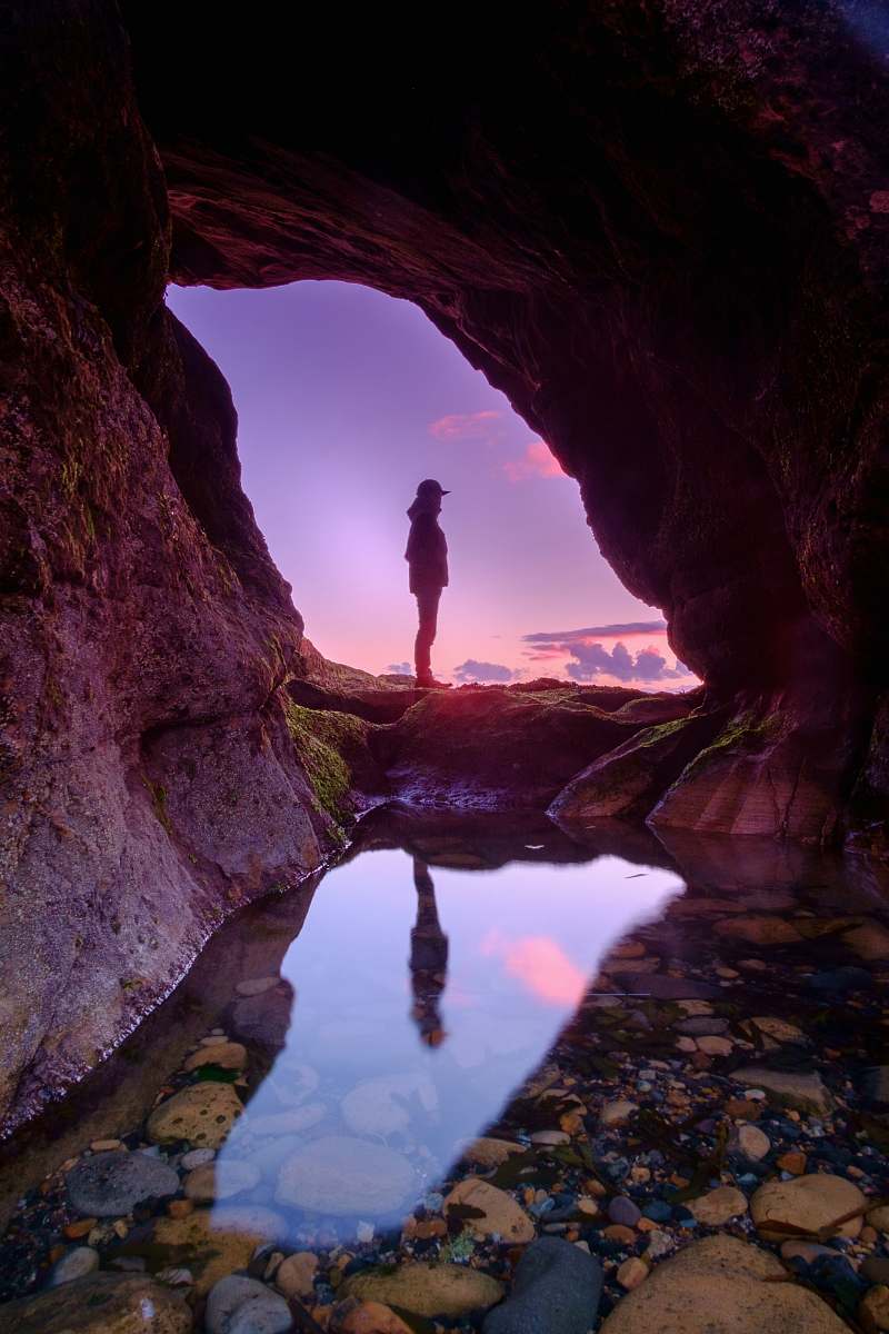 cave man standing in front of cave purple