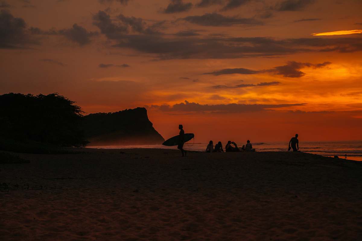 outdoors silhouette of man holding surfboard by the beach sunset
