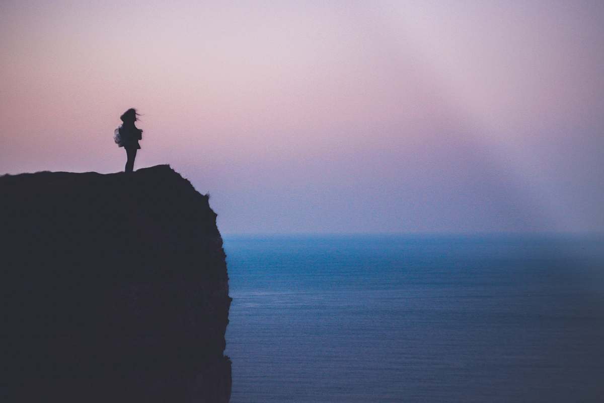 outdoors silhouette of person standing on sea cliff during golden hour cliff