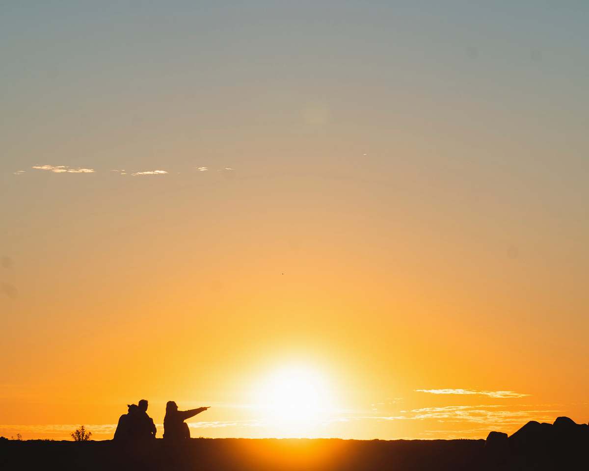 outdoors silhouette of three people sitting on land during golden hour light