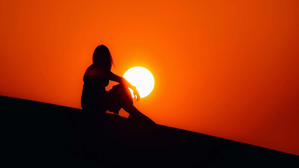 outdoors silhouette of woman sitting on ground sun
