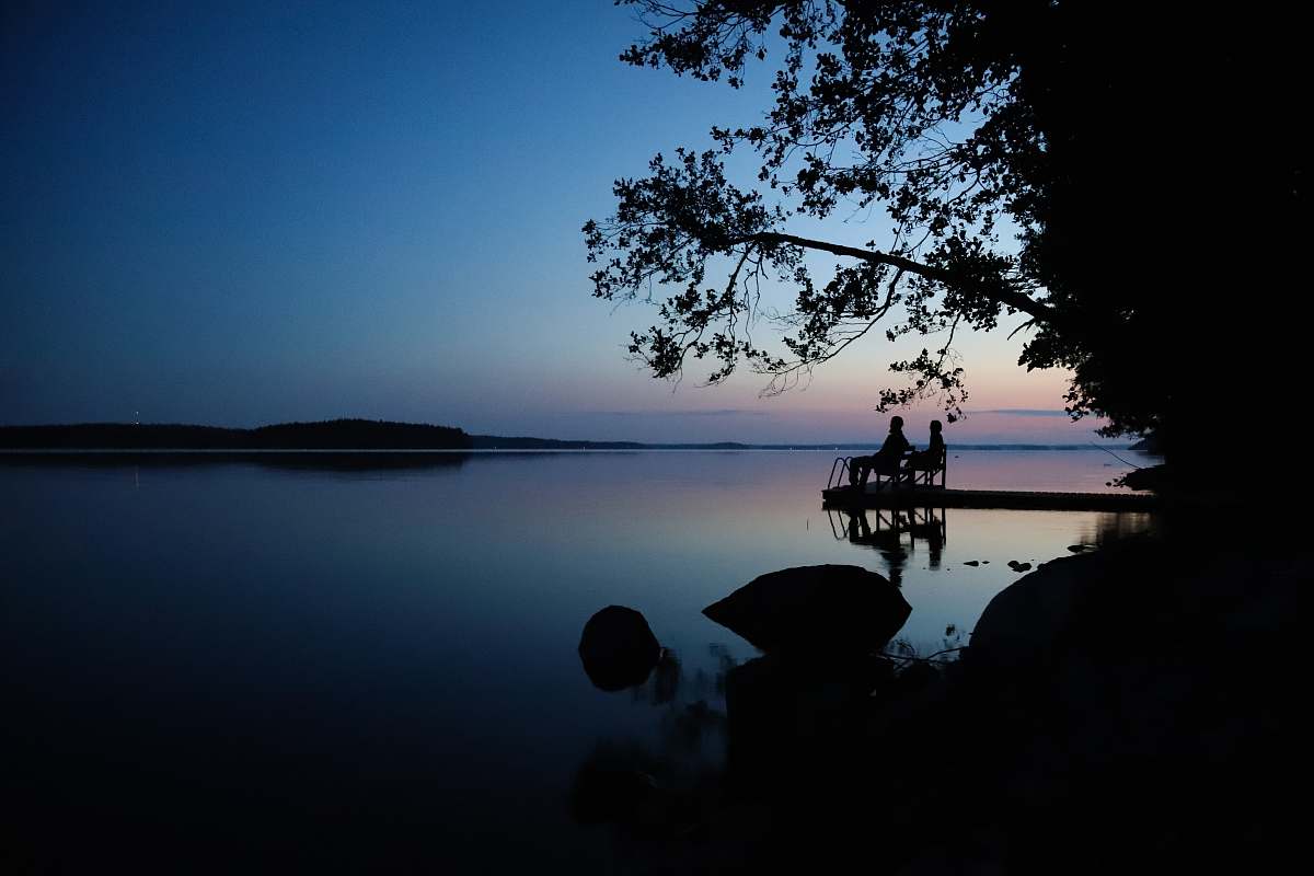 silhouette silhouette photography of two men sitting by the sea during daytime water