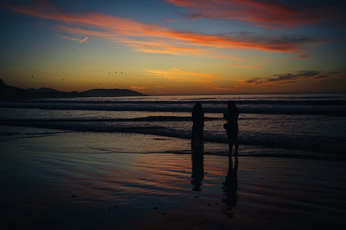 outdoors two person walking on shore during golden hour silhouette