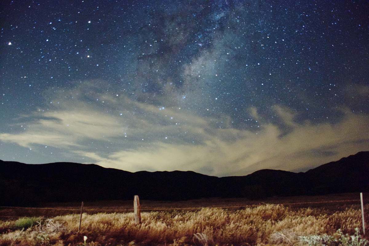 stars lawn field near mountain under cloudysky milky way
