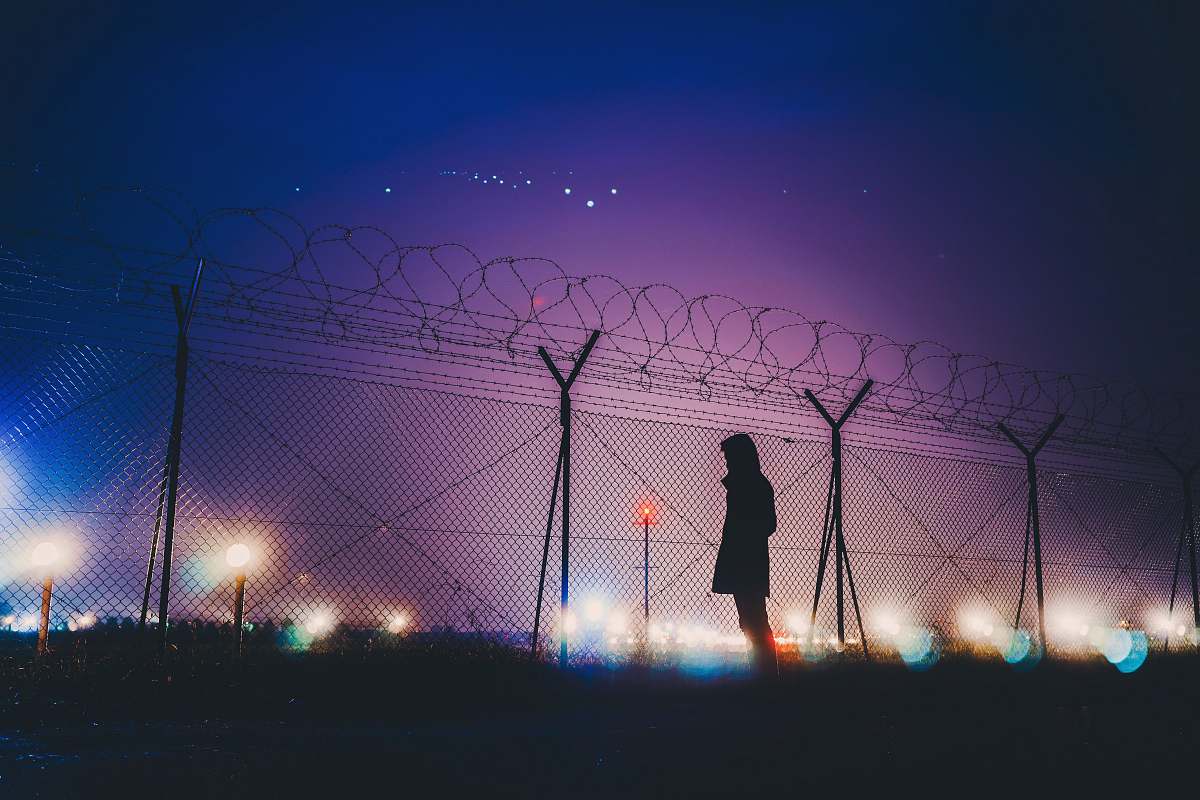 silhouette person's silhouette standing near chain link fence night light