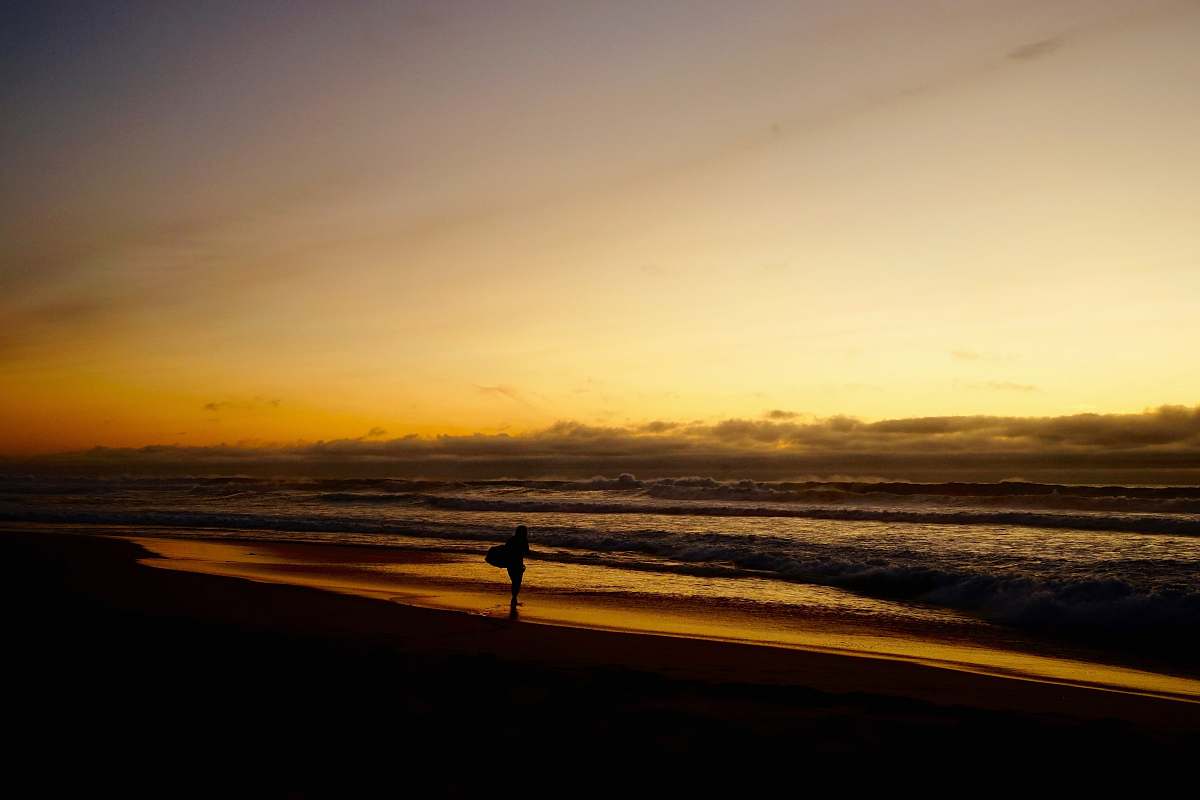 beach person standing on sea shore during golden hour coast
