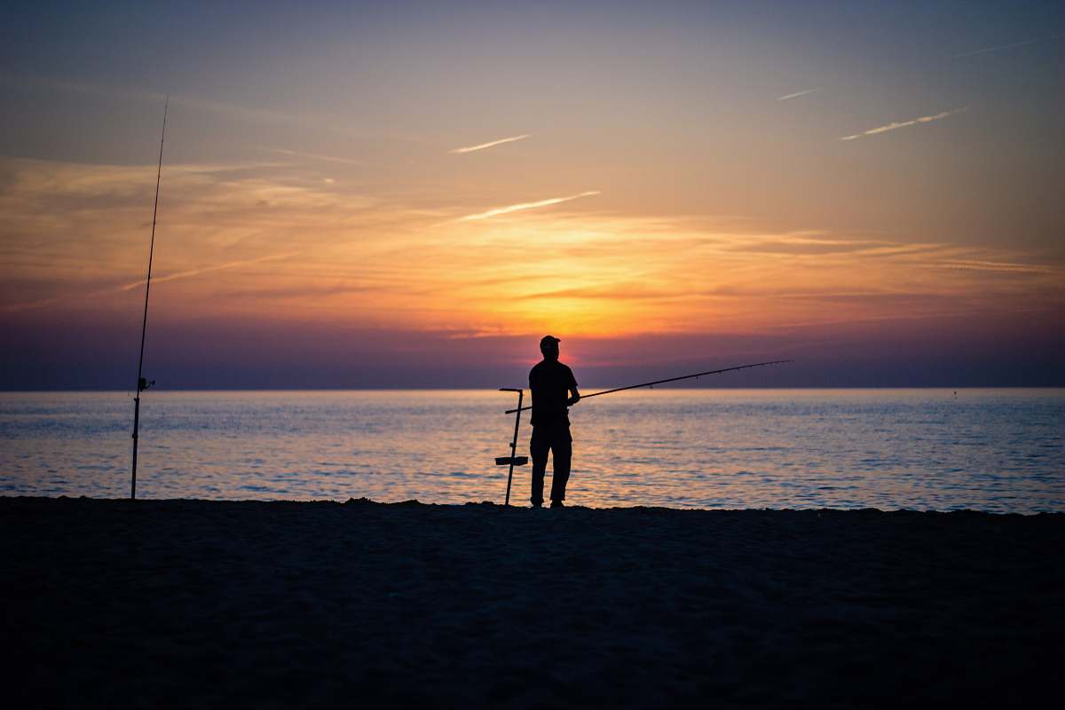 human silhouette of person standing near body of water during golden hour person