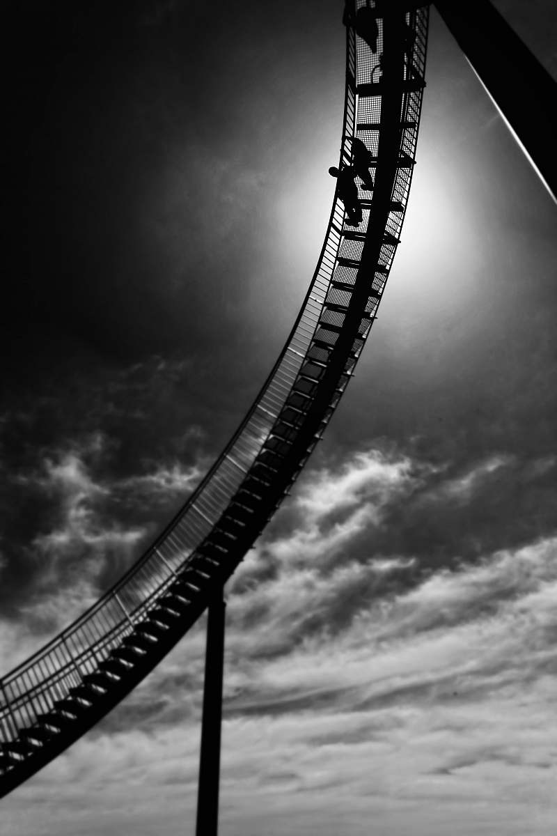 black-and-white garyscale of two person standing on metal stai coaster