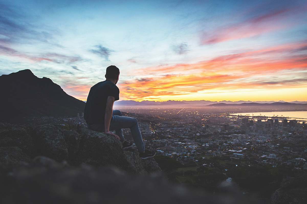 person man sitting on rock in front of sea cape town