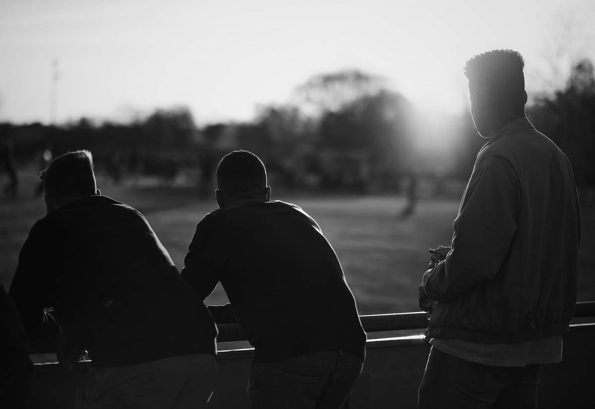 human grayscale photography of three men standing near railings black-and-white